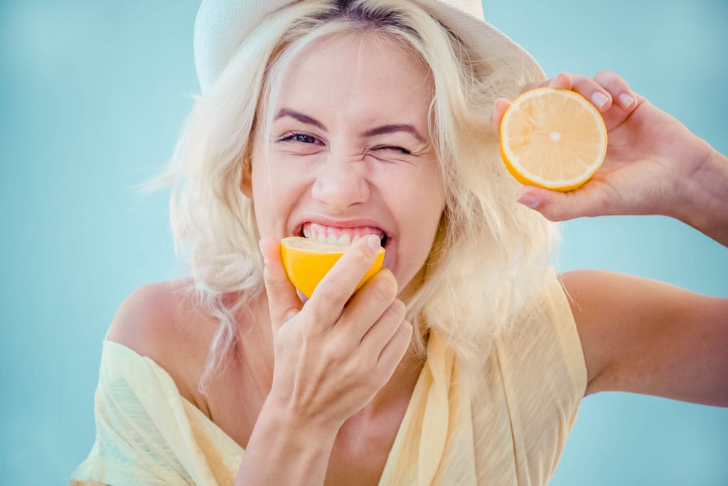 Woman biting into a lemon.